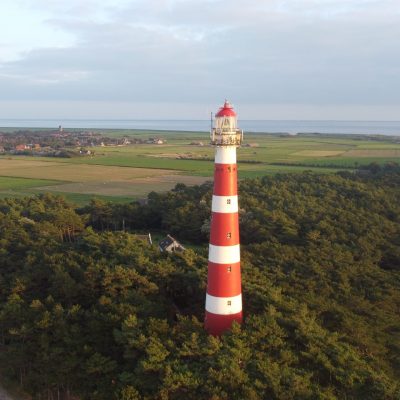 A beautiful aerial view of the Bornrif Lighthouse surrounded by lush trees in Ameland, the Netherlands